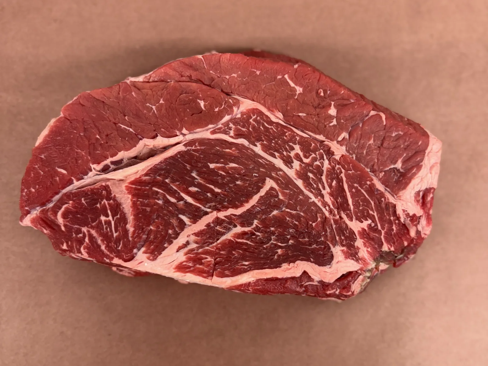 A chuck steak on butcher paper, showing the blade seam